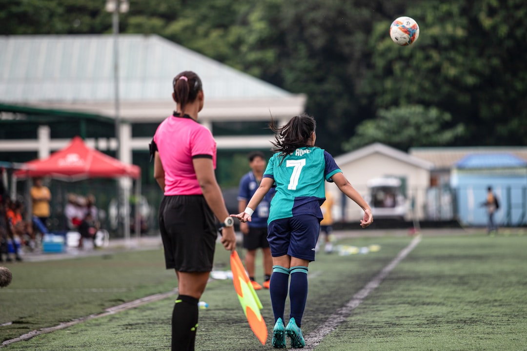 A girl in a soccer uniform jumps for a ball